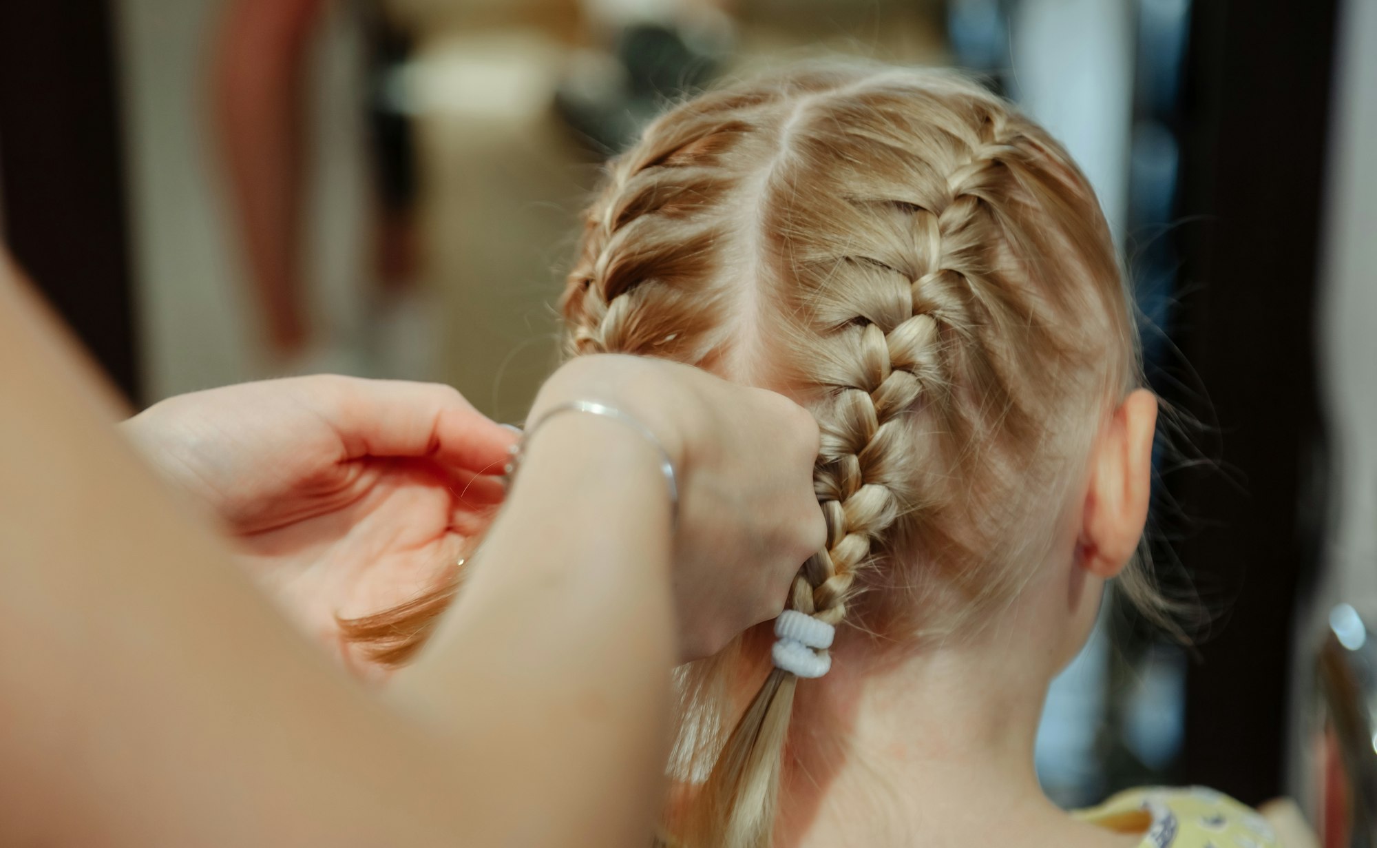 A hairdresser makes a hairstyle for a little girl in a beauty salon